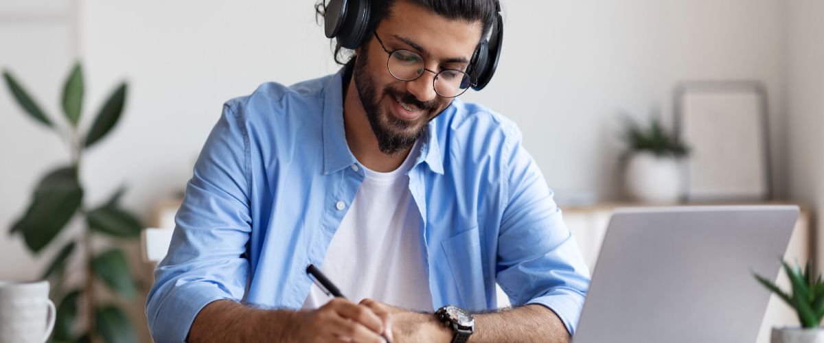 Ein Mann vor einem Laptop füllt ein Dokument aus.